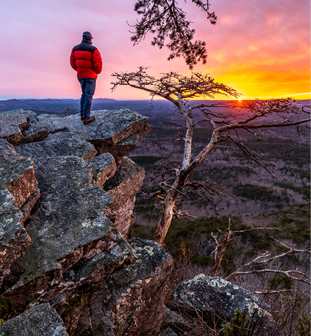 Man, person, standing on a rock high above a valley watching the sun setting in the distance, Pulpit Rock, Cheaha State Park, Alabama