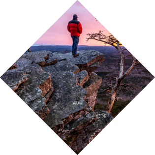 Man, person, standing on a rock high above a valley watching the sun setting in the distance, Pulpit Rock, Cheaha State Park, Alabama