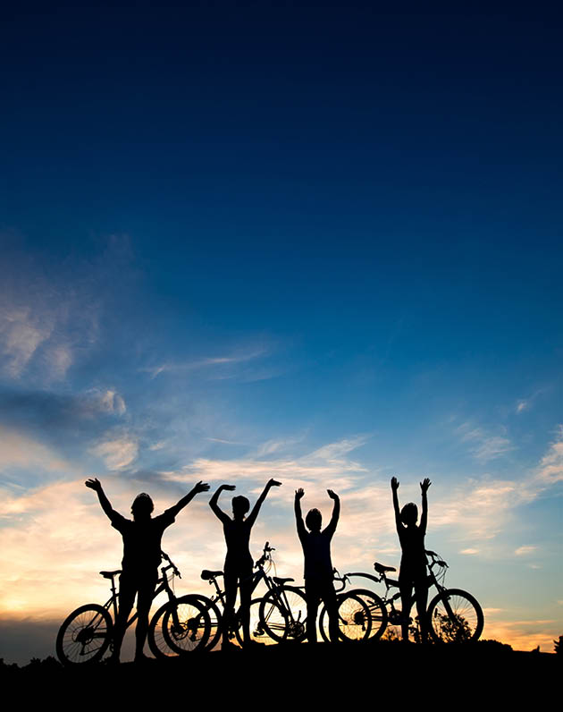 Friends with bikes at sunset background  Silhouettes of cyclists resting on evening sky background  Amazing summer evening scenery 