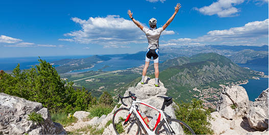 Cyclist on the top of a hill with their hands up