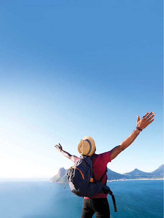 Rear view portrait of young african guy with hat and backpack standing outdoors with arms spread open