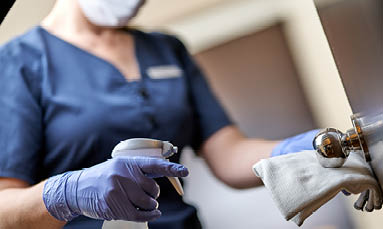 Cropped photo of chambermaid wearing gloves and wiping the door handle with a special disinfectant  Hotel service concept