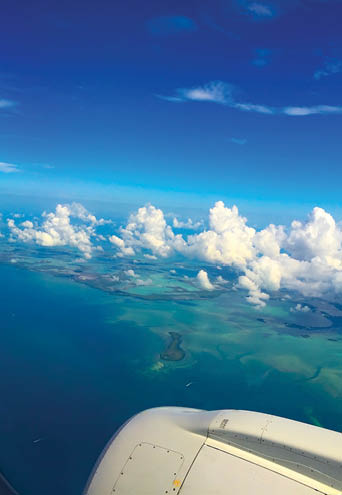 turquoise ocean and beautiful puffy white clouds welcomes vacationer to the island