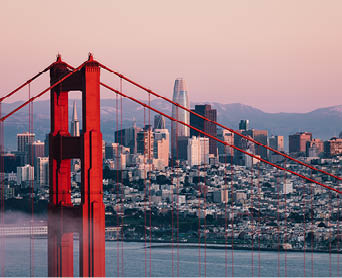 Golden Gate Bridge tower with San Francisco's skyline in background.