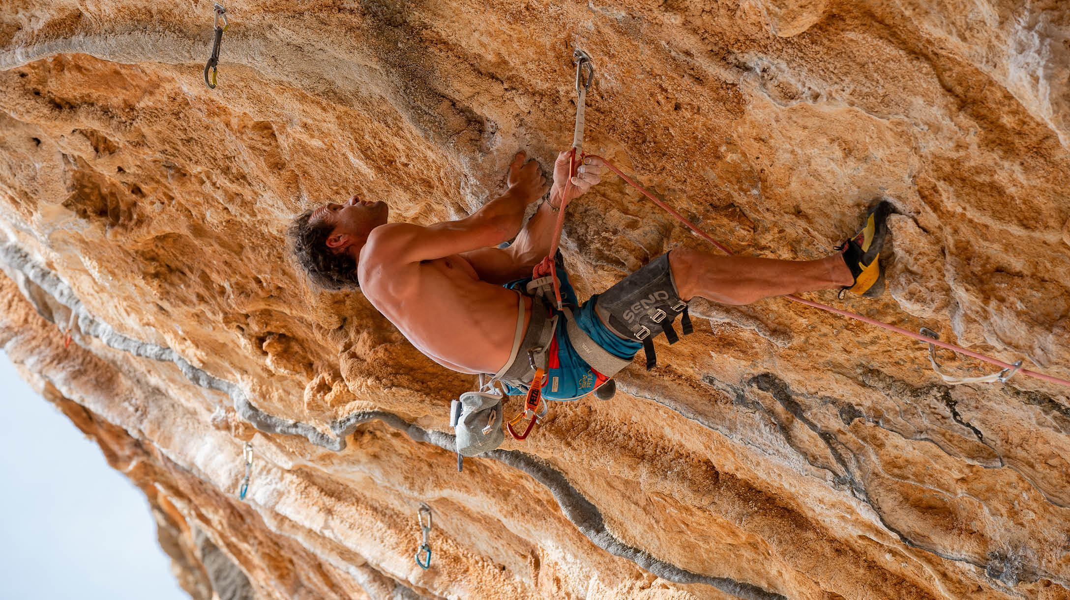 Swiss professional climber and alpinist Roger Schaeli clips the rope on the steep limestone climbing routes in Leonidio, Greece. Leonidio is a major rock climbing destination about 4 hours from Athens on the coast of Greece.  It is known for steep limestone sport climbing.