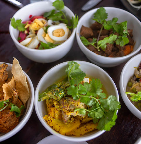 Premium creole cuisie in Le Chamarel restaurant, Mauritius. Authentic Creole cuisine surrounded by nature, from the forest to the mountains and the ocean beyond. Basket of Mauritian ‘gadjacks’ : samoussas, chilli bites, taro fritters Panier de ‘gadjacks’ à la mauricienne : samoussas, gâteaux piment, beignets d’arouille  Chamarel Palm heart salad, marinated prawns and mango dressing Salade de c ur de palmier de Chamarel, crevettes marinées et sauce à la mangue  Thin slices of smoked marlin on a bed of crispy green papaya salad Fines tranches de marlin fumé et sa salade de papaye verte croquante