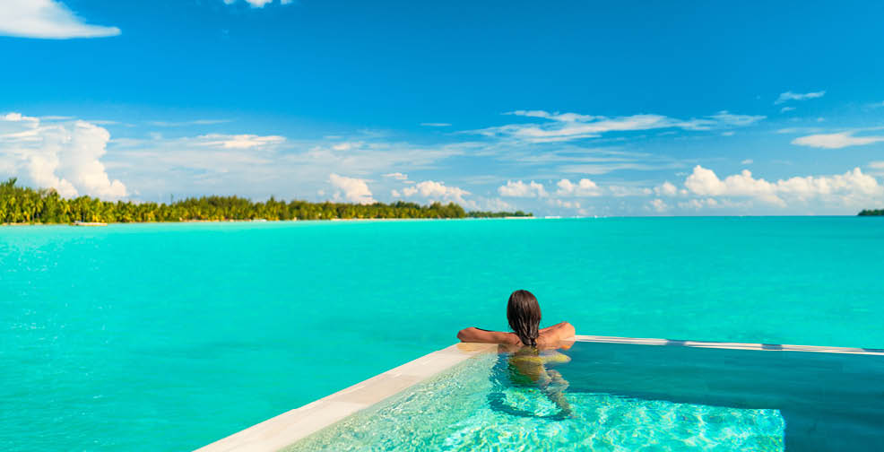 Luxury swimming pool spa resort travel honeymoon destination woman relaxing in infinity pool at hotel nature background summer holiday.