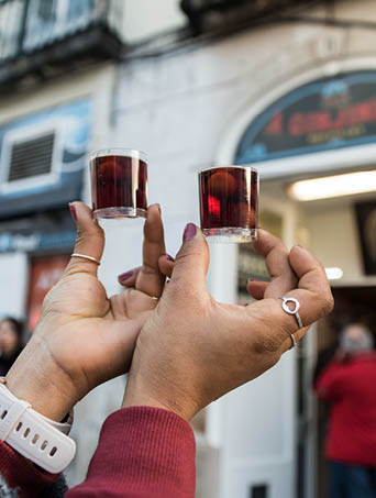 Tourist hands drink Ginjinha or ginja traditional portuguese cherry liqueur