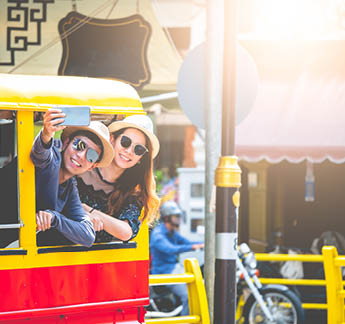 A couple of blogger tourists from Southeast Asia  Visit Phuket in Thailand are selfies on tuktuk  Captured in the old town of Phuket during write travel reviews with sunlight in travel concept 