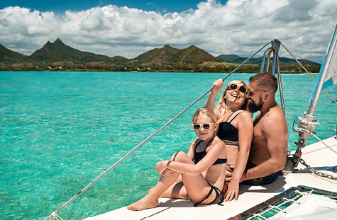 a happy family in swimsuits sits on a catamaran in the Indian Ocean. portrait of a family on a yacht in the coral reef of Mauritius.