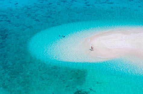 couple of men and women at a white sandbank in the ocean of Koh Lipe Island Southern Thailand, with turqouse colored ocean and white sandy beach sandbar at Ko Lipe.