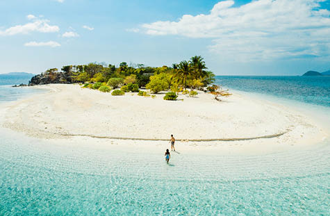 Couple on a tropical beach with blue water and palm trees - Coron, Philippines