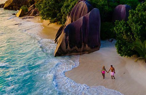 Anse Source d'Argent, La Digue Seychelles, a young couple of men and women on a tropical beach during a luxury vacation in Seychelles. drone view from above at a tropical beach
