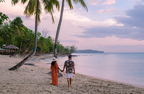 couple on the beach with palm trees watching the sunset at the tropical beach of Saint Lucia or St Lucia Caribbean. men and women on vacation in St Lucia a tropical island with palm trees