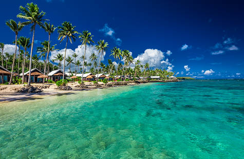 Tropical beach with with coconut palm trees and villas on Samoa Island