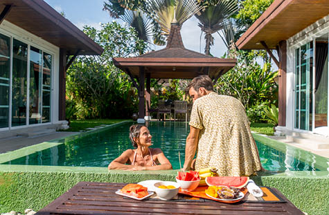 Couple of lovers in a beautiful villa with swimming pool in a tropical climate location - Happy people on a summer vacation, influencers enjoying a luxury resort
